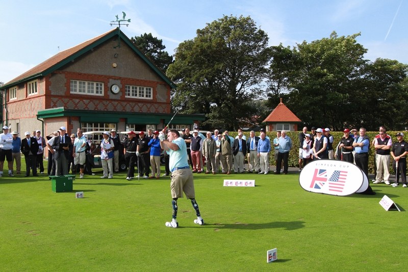 A golfer with prosthetic legs demonstrating a swing to a group watching beside the green